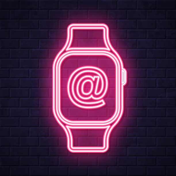 带有At符号的智能手表。在砖墙背景上发光的霓虹灯图标图片下载