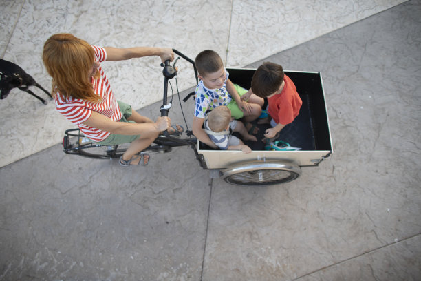 上图是一位母亲骑着三个孩子骑货运自行车的照片图片下载