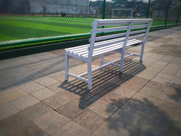 足球场围栏外的白色长凳图片下载