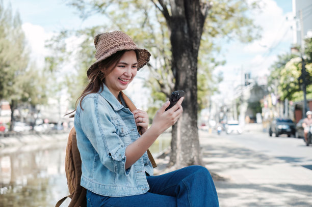 年轻的亚洲游客走在城市街道上，在人行道上拿着手机。电话沟通。查看社交网络，发短信图片下载