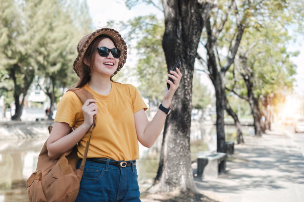 年轻的亚洲游客走在城市街道上，在人行道上拿着手机。电话沟通。查看社交网络，发短信图片下载
