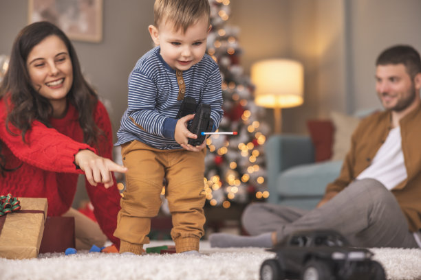 蹒跚学步的孩子正在学习玩遥控汽车玩具，他得到了圣诞礼物图片下载