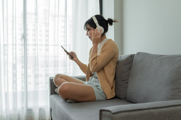 HappyÂ年轻的亚洲女子戴着耳机Â听着音乐在客厅放松图片下载