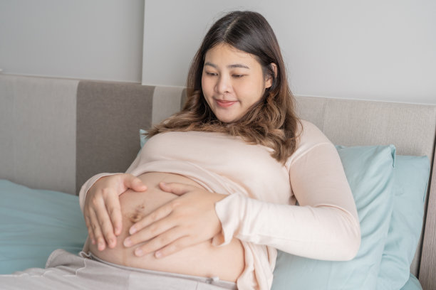 怀孕的亚洲妇女双手放在肚子上抚摸她的孩子，关心她的健康美丽快乐怀孕womanÂ温柔的心情怀孕照片图片下载