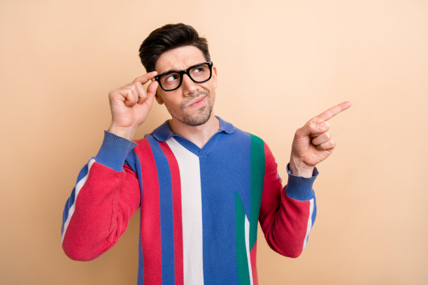 照片中的年轻人思考时，指导他的手指空白的空间信息猜测发生了什么孤立的米色背景图片下载