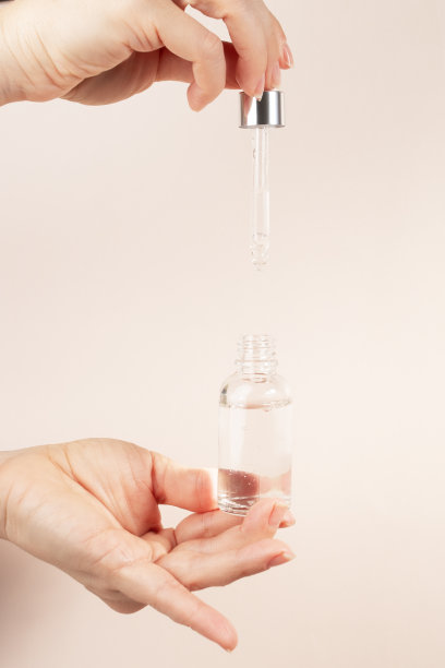 精华液，女性双手滴油到手指上的米色自然底色，面部保湿精华液，抗衰老，面部化妆品图片下载