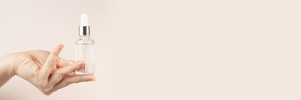 女性手上的精华液，米色自然底色，面部保湿精华，抗衰老，面部彩妆，旗帜图片下载