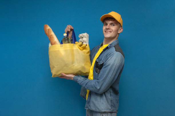 一个快乐的购物者拿着一个蓝色背景的织物环保袋，一个男人拿着一个装满杂货的非塑料袋图片下载
