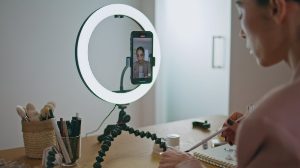 视频博主女孩用智能手机流媒体化妆特写。博主画唇图片下载