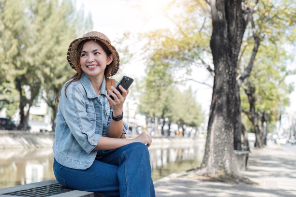年轻的亚洲游客走在城市街道上，在人行道上拿着手机。电话沟通。查看社交网络，发短信图片下载