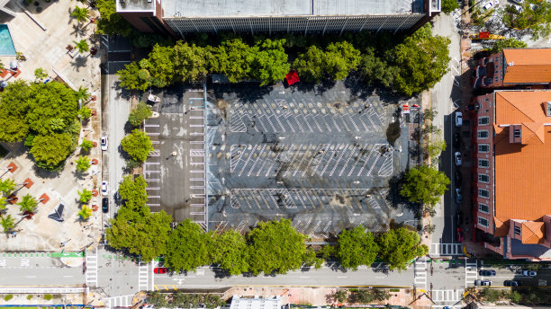 在晴朗的夏日，市中心空旷的停车场几乎没有车辆。未使用的空间以道路标记划分为独立空间，周围有树木图片下载