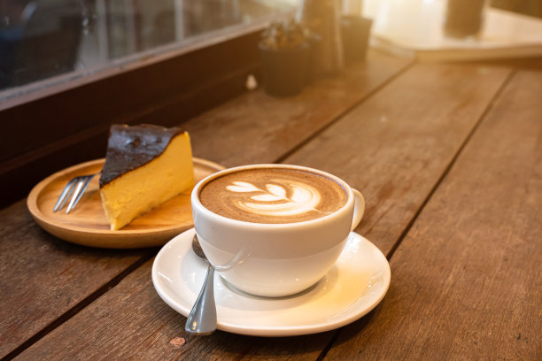 热咖啡拿铁与拉花艺术牛奶泡沫在杯杯和自制巧克力蛋糕木桌木桌上的顶部视图。如早餐在咖啡厅咖啡厅，商务期间工作概念图片下载