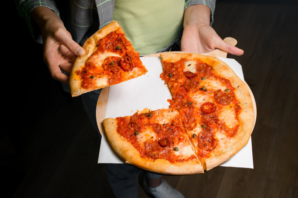 女服务员拿着木制的餐盘，上面放着刚烤好的辣香肠披萨，然后取下一块图片下载