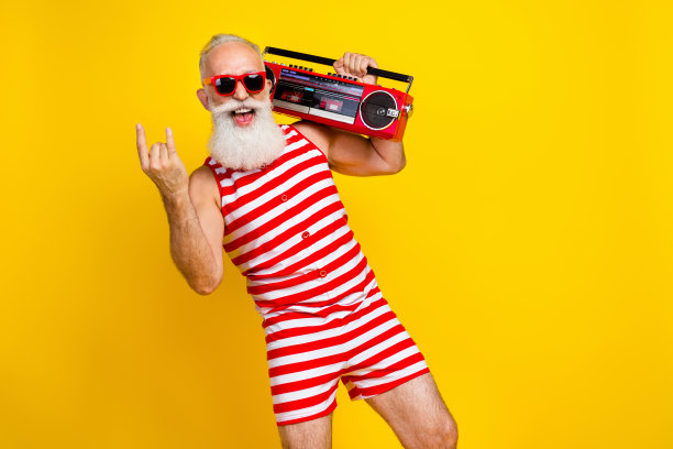 疯狂野蛮的祖父穿着条纹红色泳衣的照片显示摇滚金属标志与音箱孤立在黄色背景图片下载