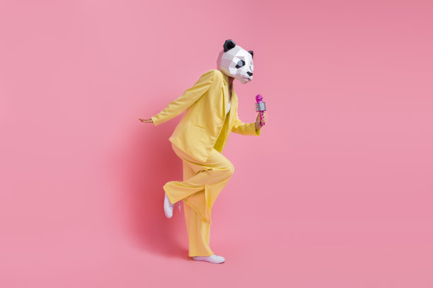全身侧面肖像魅力怪异3d熊猫面具女士拿着麦克风唱歌跳舞孤立在粉红色的背景图片下载
