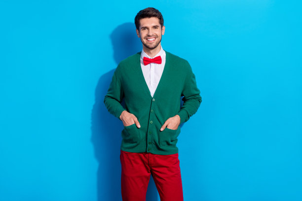 照片中时髦的好心情男人穿着圣诞绿色开衫微笑孤立的蓝色背景图片下载
