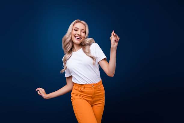 照片中，开朗可爱的女孩穿着时髦的白色衣服，在深蓝色的背景下跳着新年圣诞派对图片下载