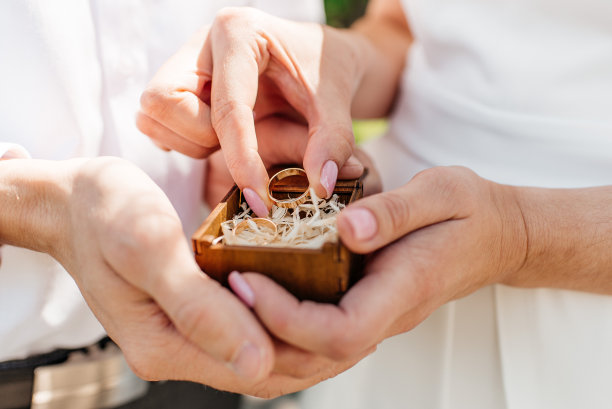 一男一女戴着结婚戒指的照片。年轻的新婚夫妇手牵着手，举行婚礼。新婚夫妇戴着结婚戒指的手。图片下载