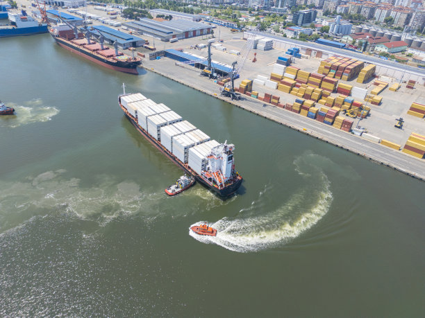 拖船在集装箱船进港时跟着它。国际海洋运输。图片下载