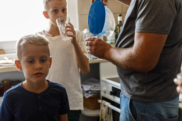 一个男人在厨房给他的两个儿子倒水图片下载