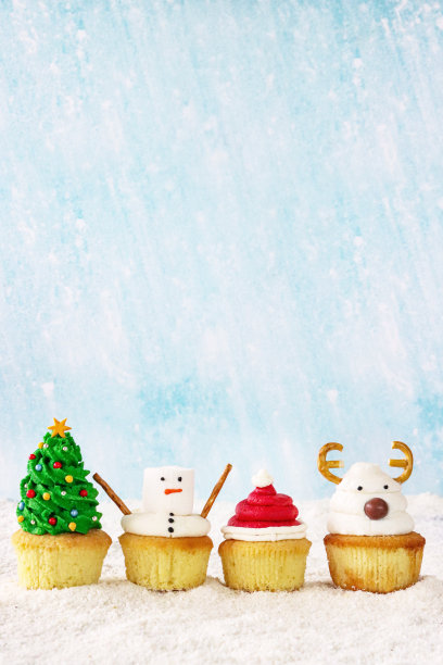 图片一行四张，自制，圣诞设计纸杯蛋糕，圣诞树，雪人，圣诞老人帽和驯鹿装饰的蛋糕，糖霜雪，淡蓝色背景，重点放在前景，复制空间图片下载