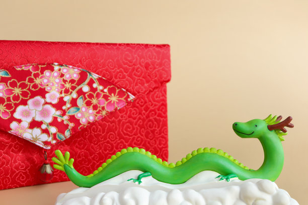 浅棕色背景下的春节绿龙雕像和红包。2024年新年。图片下载