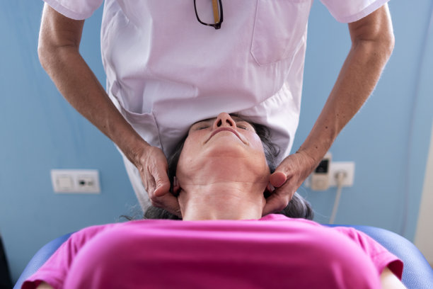 一位中年妇女的脸部特写照片，护士正在给她做颈部按摩。图片下载