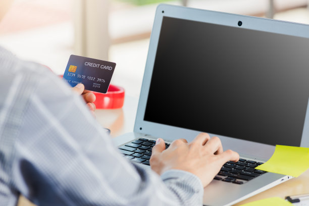 商人手里拿着信用卡，在笔记本电脑上输入安全码图片下载