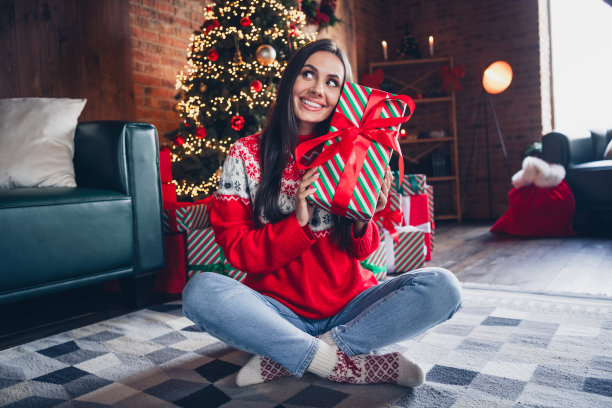 梦幻可爱的女孩坐在地板上毛茸茸的地毯包装礼物的朋友和家人享受神奇的季节在室内的照片图片下载