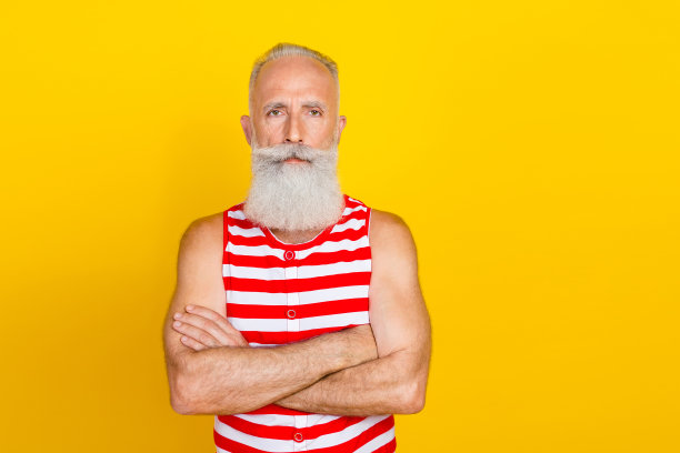 照片中自信酷炫的高级男子穿着红色条纹泳衣双臂交叉，空白空间孤立的黄色背景图片下载