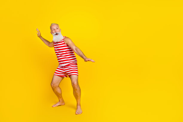 穿着条纹泳衣冲浪的老人在大海中保持平衡的全身照片，在黄色背景上看起来很空旷图片下载