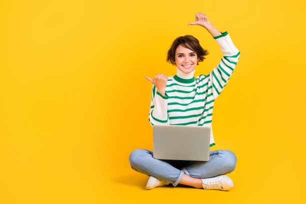 年轻的推动者女孩的全身照片笔记本电脑直接手指网络产品在线服务折扣为学生孤立的黄色背景图片下载