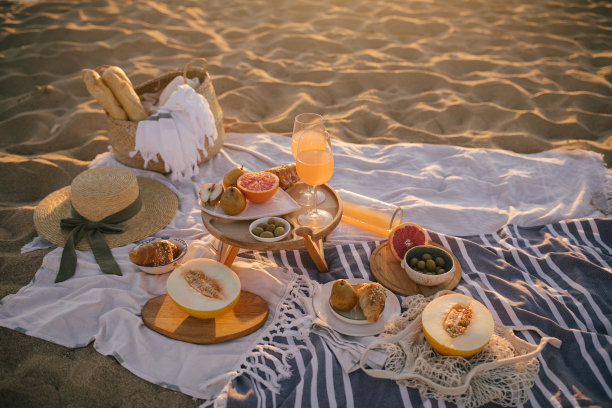 美丽美味的野餐，柠檬水，新鲜水果和牛角面包在日落的海滩。图片下载