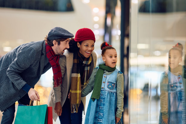 圣诞节期间，一个黑人小女孩和她的父母在购物中心看橱窗。图片下载