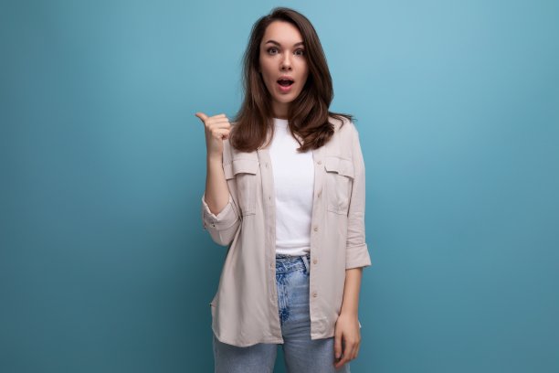 在一张时髦的图片中，聪明的黑发年轻女子用手指指着带有复制空间的蓝色背景图片下载