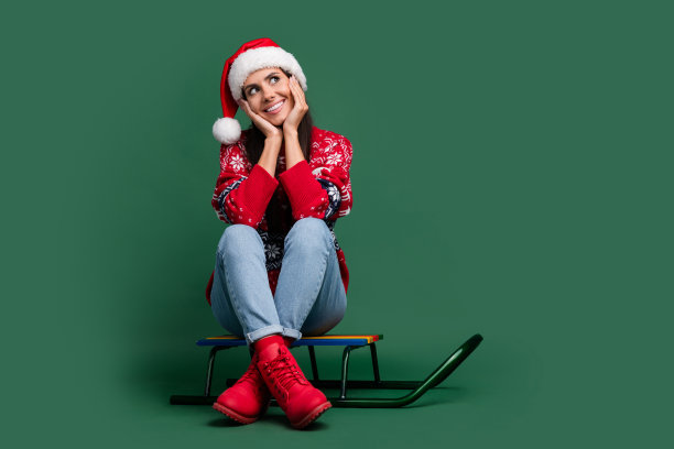 全尺寸照片的年轻可爱的女孩触摸脸颊梦见空的空间骑雪橇圣诞老人孤立的绿色背景图片下载