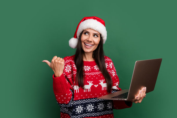 照片梦幻可爱的圣诞老人助手女士穿着印花圣诞毛衣打字现代小工具拇指空白空间孤立的绿色背景图片下载