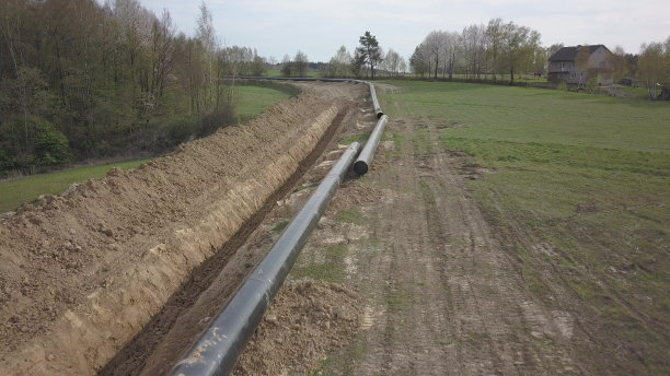 青山间铺设天然气管道。大型高压钢管在开挖的沟槽中浸没。土地在战略产业中起作用。能源和自然资源图片下载