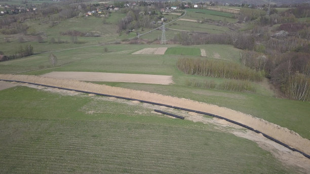 青山间铺设天然气管道。大型高压钢管在开挖的沟槽中浸没。土地在战略产业中起作用。能源和自然资源图片下载