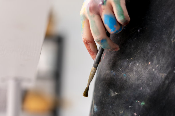 穿着黑色围裙的女艺术家拿着画笔图片下载