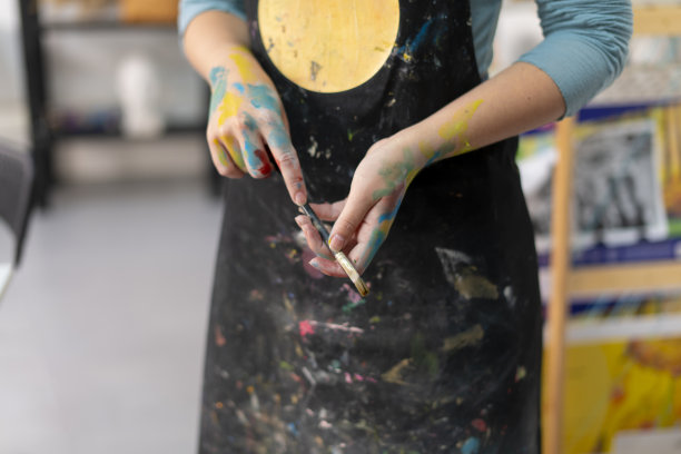 穿着黑色围裙的女艺术家拿着画笔图片下载