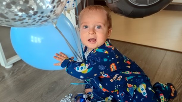 生日那天，兴奋或害怕的小男孩抱着气球在地板上爬的照片图片下载