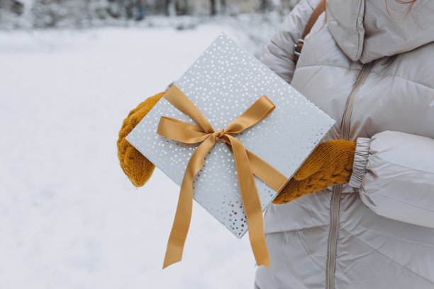 冬天，一位妇女在城市公园外拿着礼物。妇女们在户外拿着圣诞礼物。购物的概念，节日和快乐圣诞节。图片下载