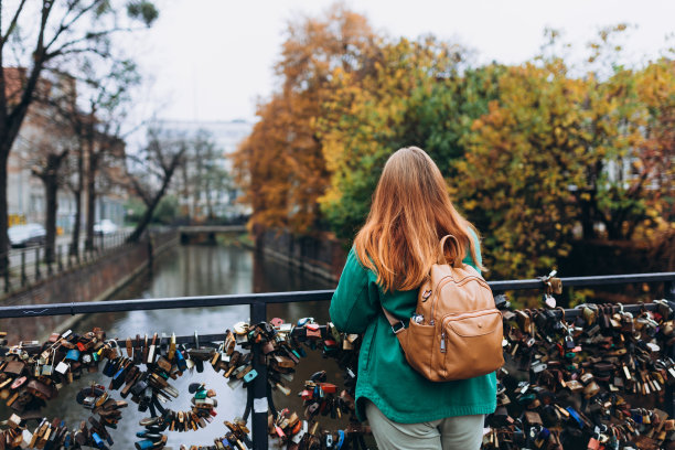 30多岁的时髦女人背着背包在城市河边放松。自由和积极的生活方式理念。高质量照片图片下载