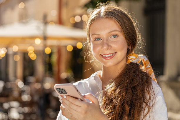 十几岁的女孩用智能手机打字短信，浏览互联网，完成工作，看着相机图片下载
