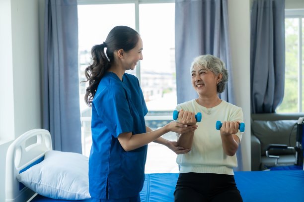 一位年轻的亚洲护士在养老院照顾一位老年妇女。主治医师为老年患者提供物理治疗服务，锻炼身体，促进健康。图片下载