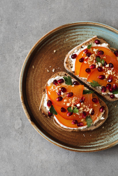 奶油芝士、柿子和石榴籽烤面包。极简主义美食照片图片下载