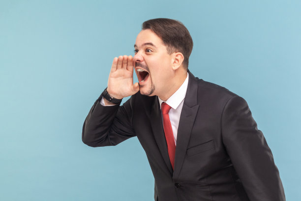 一个留着胡子的愤怒的男人站着大声尖叫，把手放在嘴边。图片下载