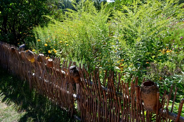 在波兰一个阳光明媚的夏日里，靠近木栅栏、蜂箱和长满鲜花、草药和其他植物的维护良好的花园的旧木屋、棚屋或庇护所的特写照片图片下载