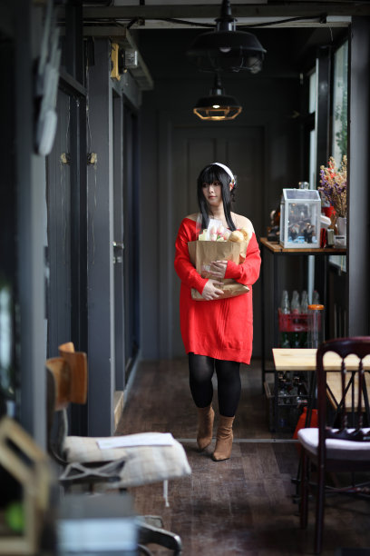 一个漂亮的年轻女人的肖像，穿着红毛衣，在走廊的购物袋里装着面包图片下载